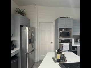 Kitchen with large refrigerator, microwave and oven plus coffee maker and tea kettle.