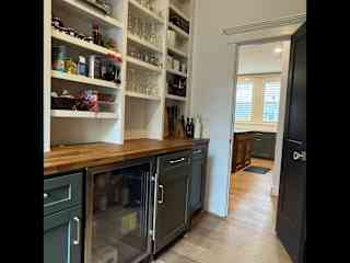 Walk in pantry with beverage refrigerator and butcher block countertops.