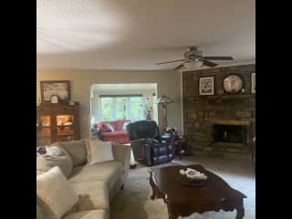 Living room and sunroom with sofa and large desk surround by windows to watch the birds.