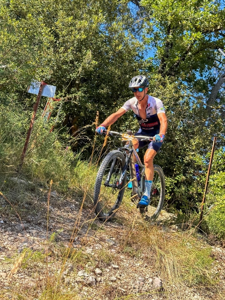 Atleta Triono in salita su un singletrack tra la vegetazione