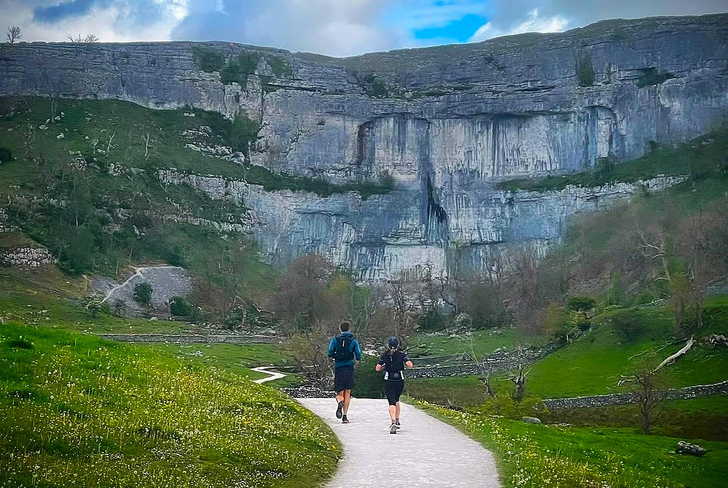 Runners approaching the limestone cliffs of Malham Cove