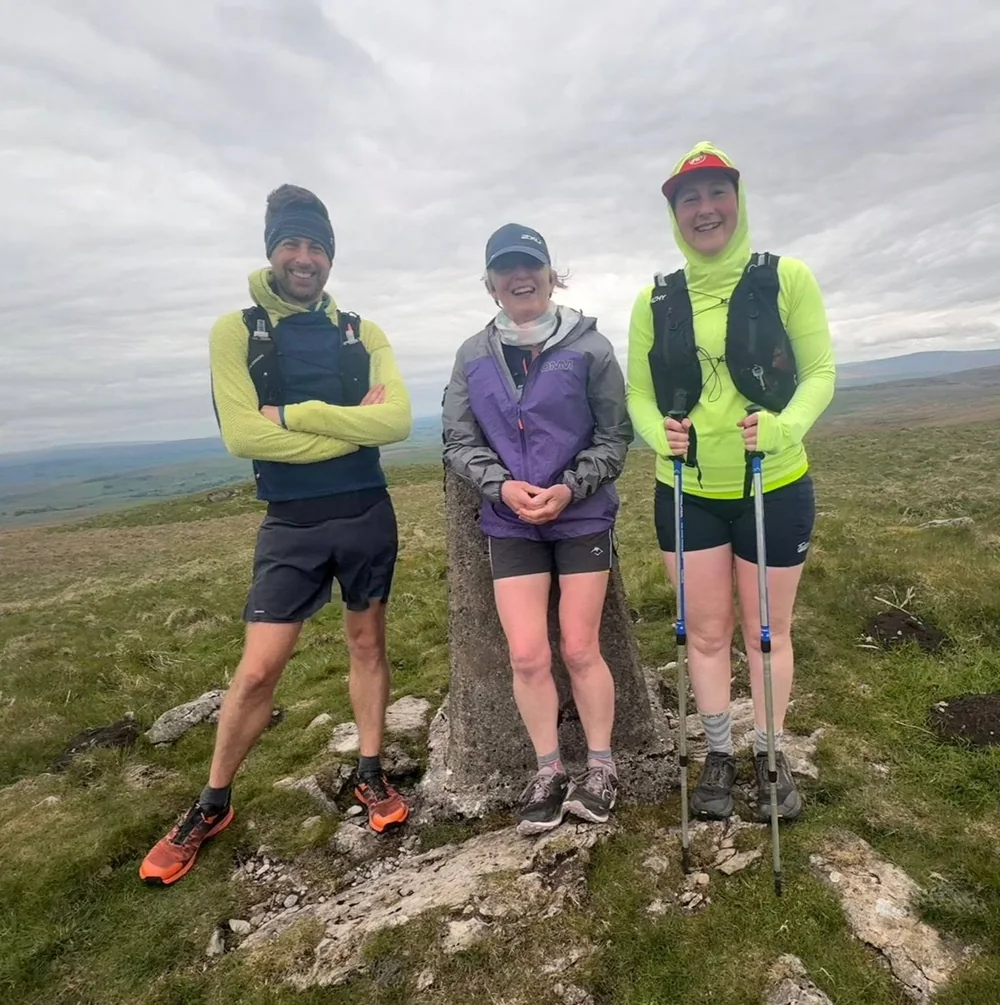 A group of runners beside a trig point