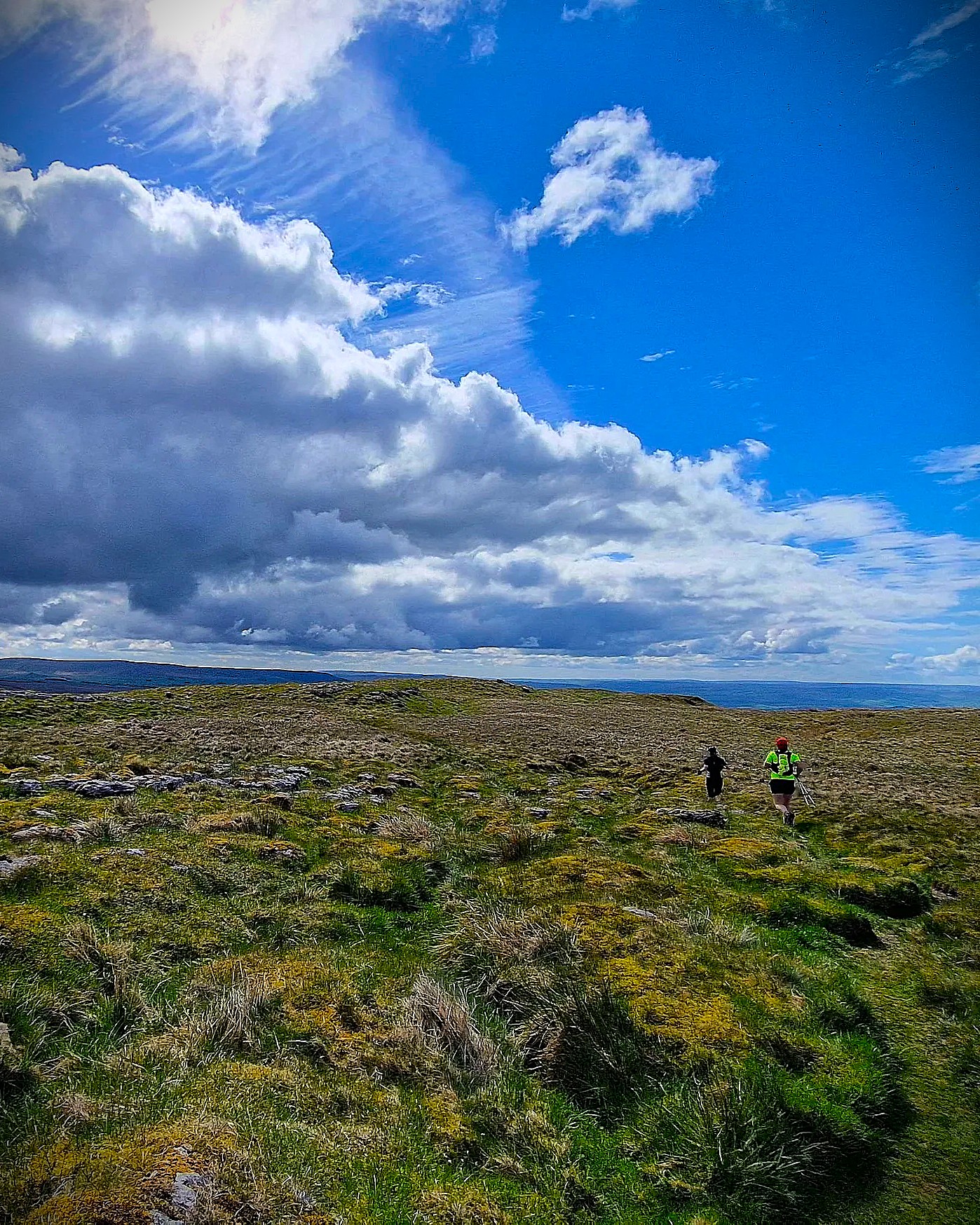 Runners crossing open limestone moorland beneath a huge Yorkshire Dales sky