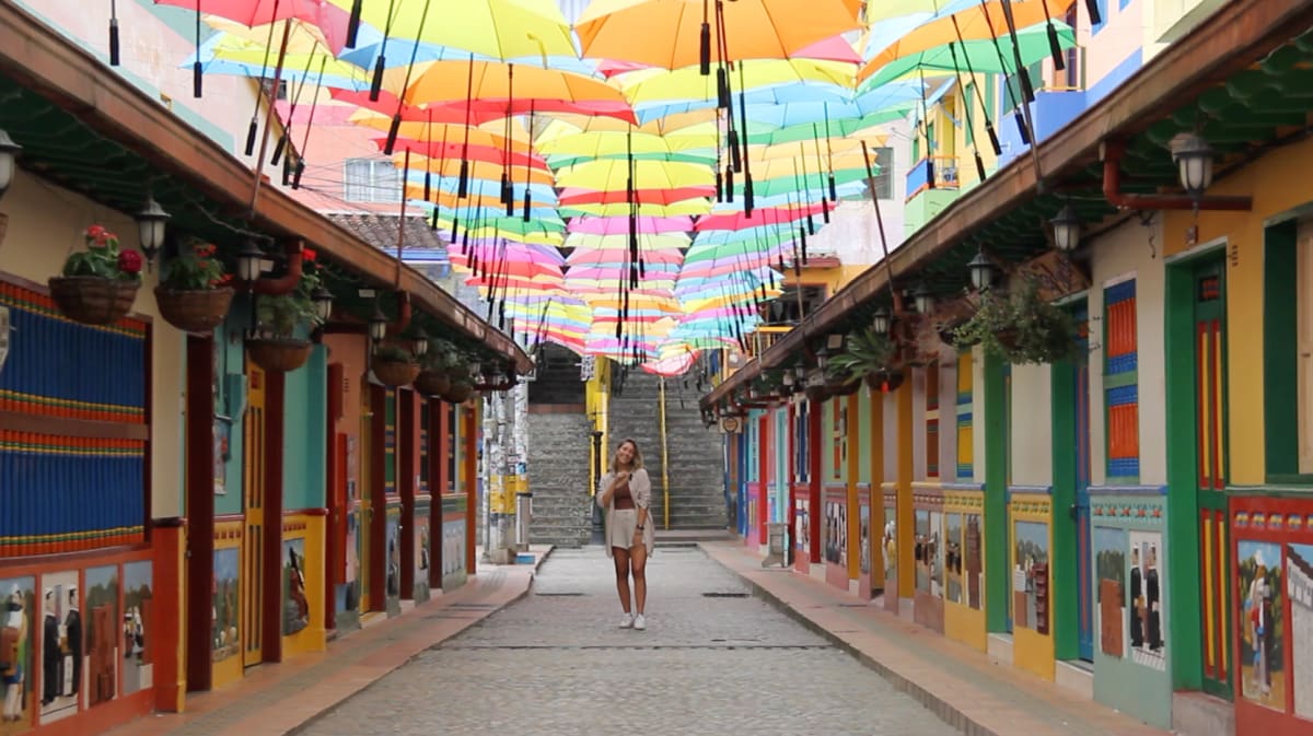 Viajera bajo las sombrillas de colores de la calle de las sombrillas de Guatapé