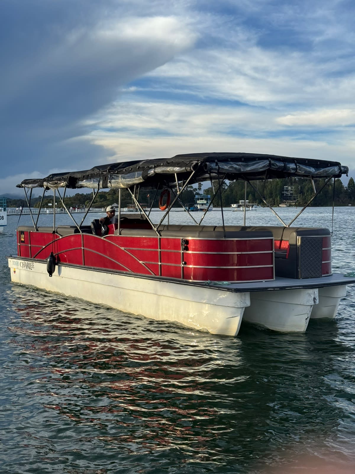 El planchón rojo para 35 personas en el embalse de Guatapé, con el conductor al timón