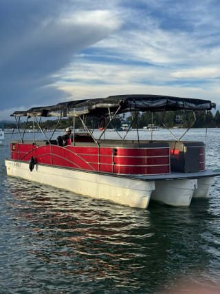 El planchón rojo para 35 personas en el embalse de Guatapé, con el conductor al timón