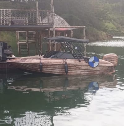 Lancha de wakeboard amarrada junto a un muelle con techo de paja