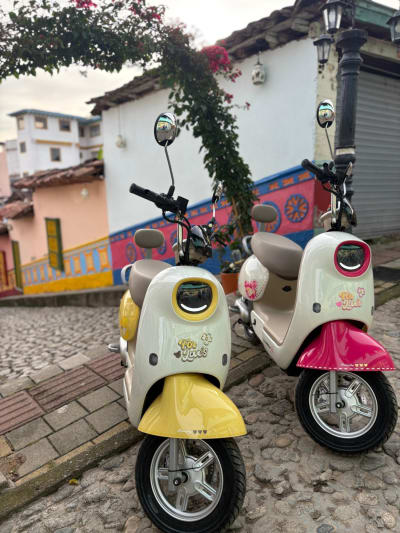 Two electric scooters parked on a colourful street in Guatapé