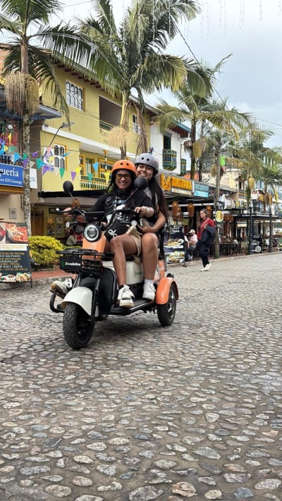 Two friends on a double electric scooter in Guatapé's main street