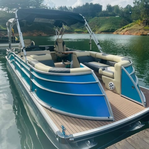 Blue pontoon boat with lounge seating docked on Guatapé Lake