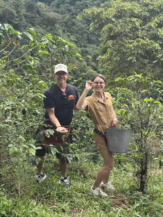 Pareja mostrando granos de café recién recogidos en la finca