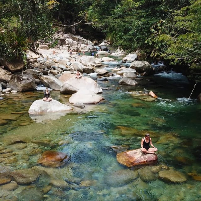 Mujer sentada en una piedra en un charco turquesa del río