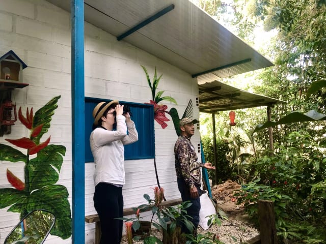 Observadores de aves en una casa campesina de colores con bebedero de colibríes cerca de Guatapé