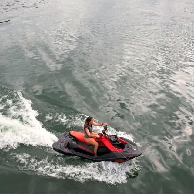 Piloto en un jet ski rojo abriendo estela en el agua