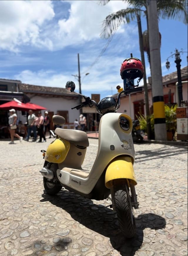 Yellow electric scooter with a red helmet by the Guatapé square