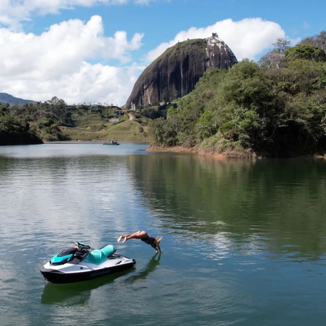 Persona lanzándose del jet ski al embalse de Guatapé con la Piedra del Peñol al fondo