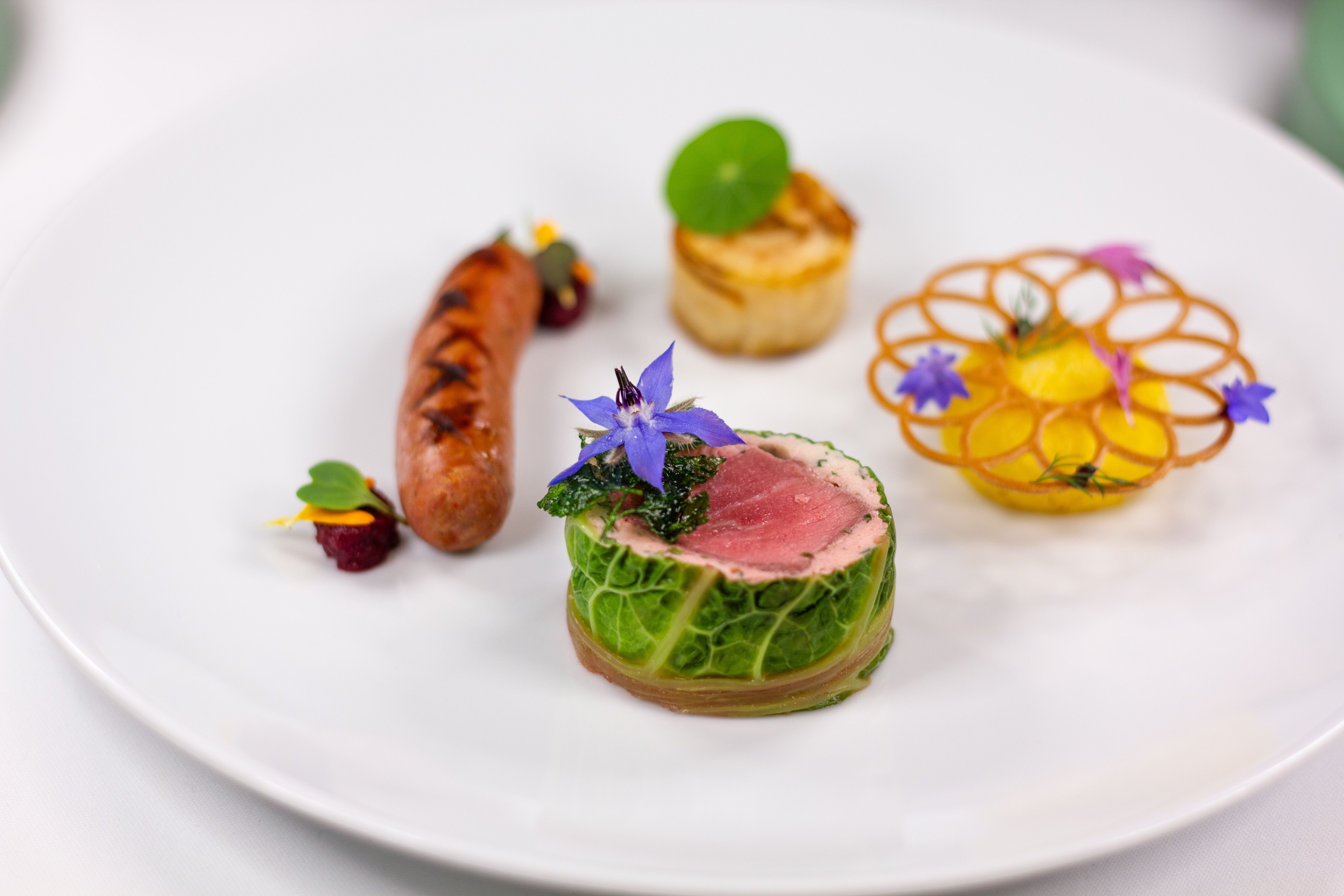 Plato de alta cocina con flores comestibles, presentación editorial