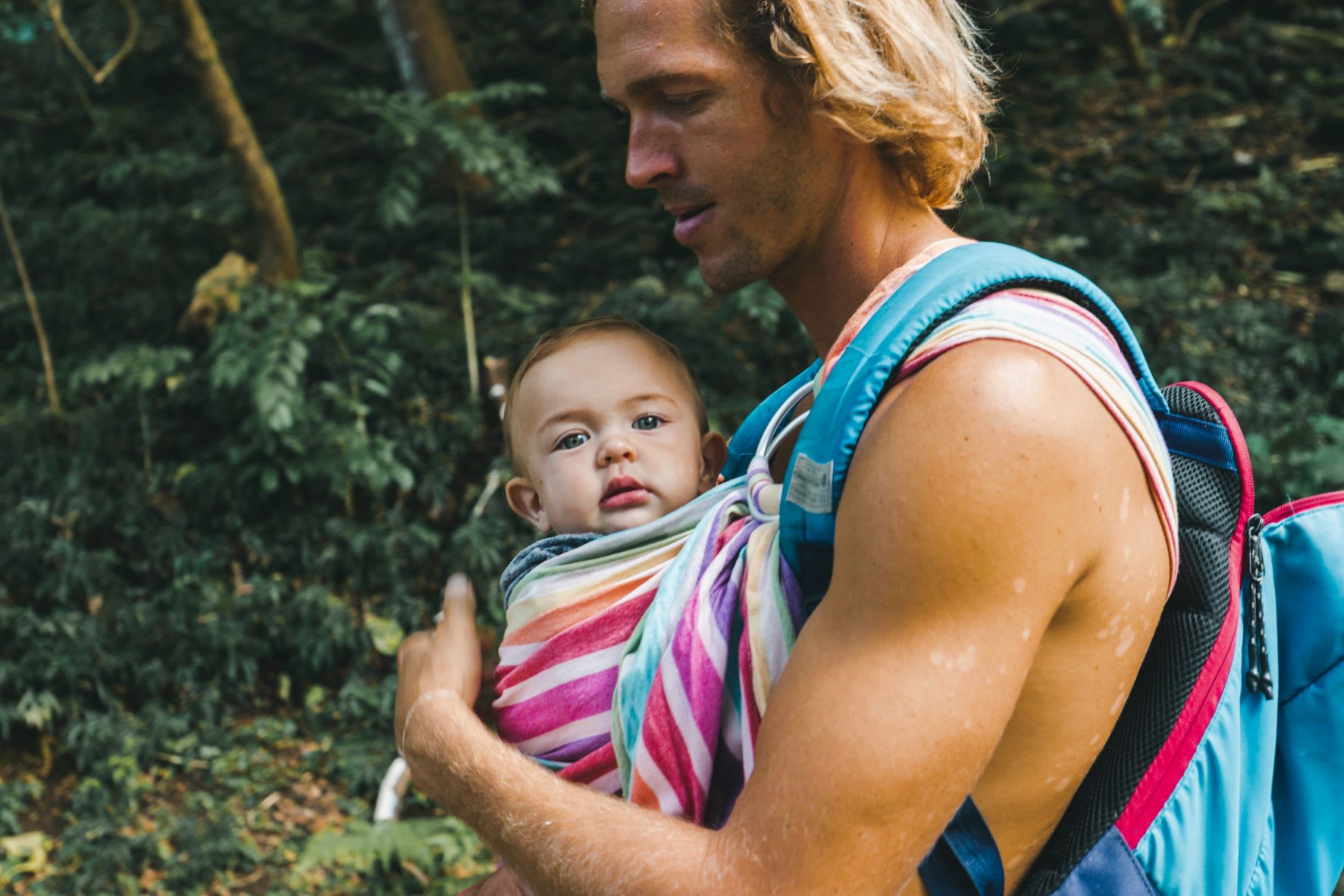 Man holding a baby in a fabric baby sling