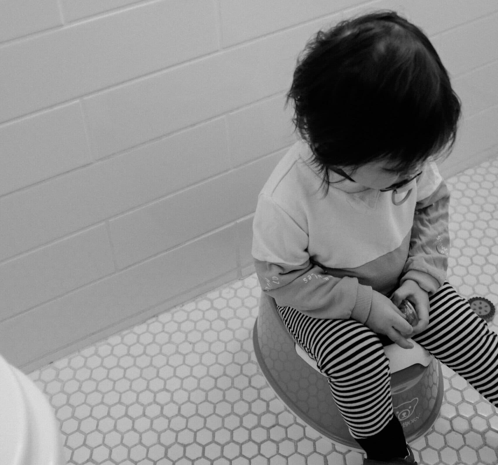 A toddler sitting on a potty. Greyscale image.