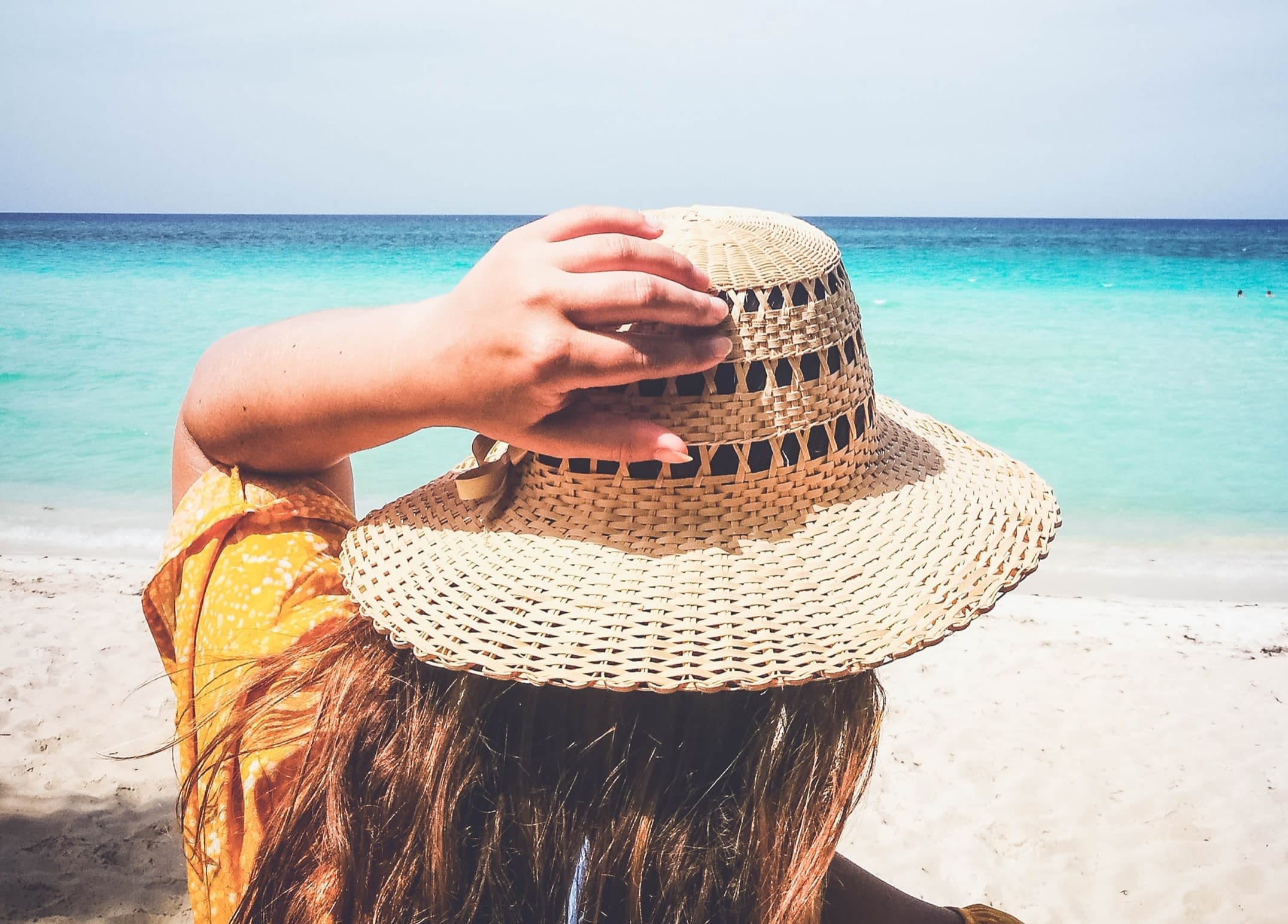 Woman wearing a second-hand straw sun hat at the beach