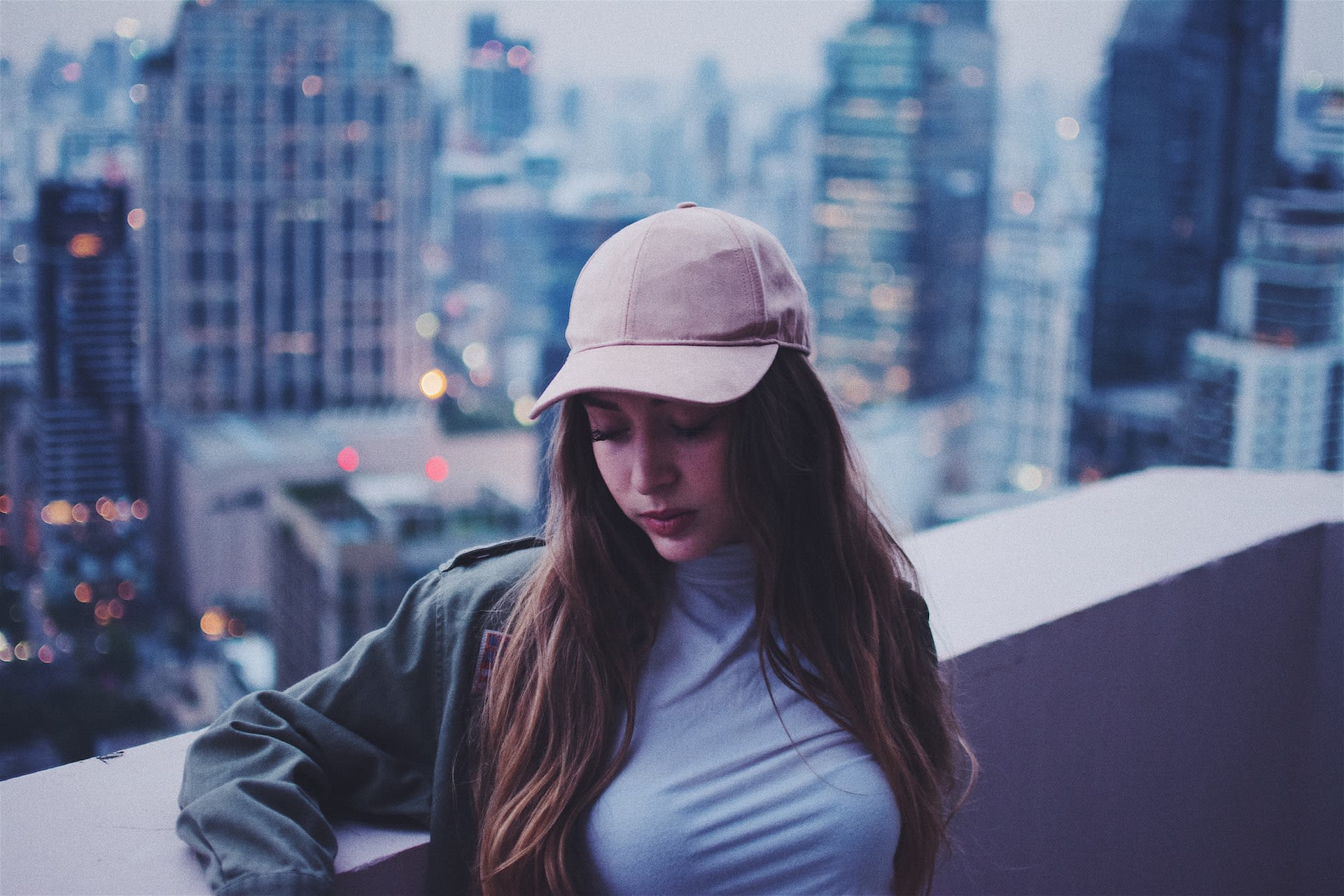 Woman wearing a pink baseball cap with a city skyline background