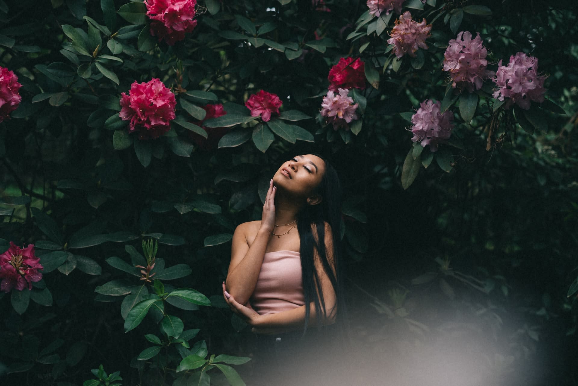 Woman wearing a pink bandeau top next to pink flowers