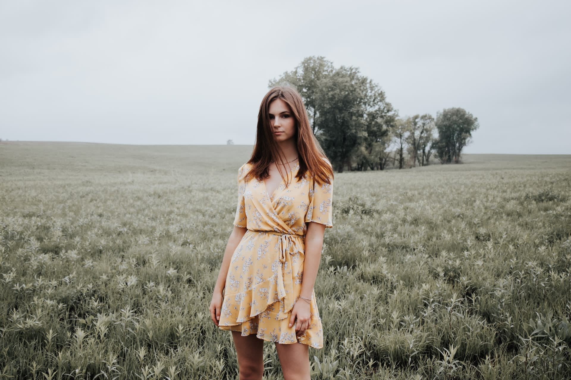 Woman wearing second-hand yellow floral mini dress in a field