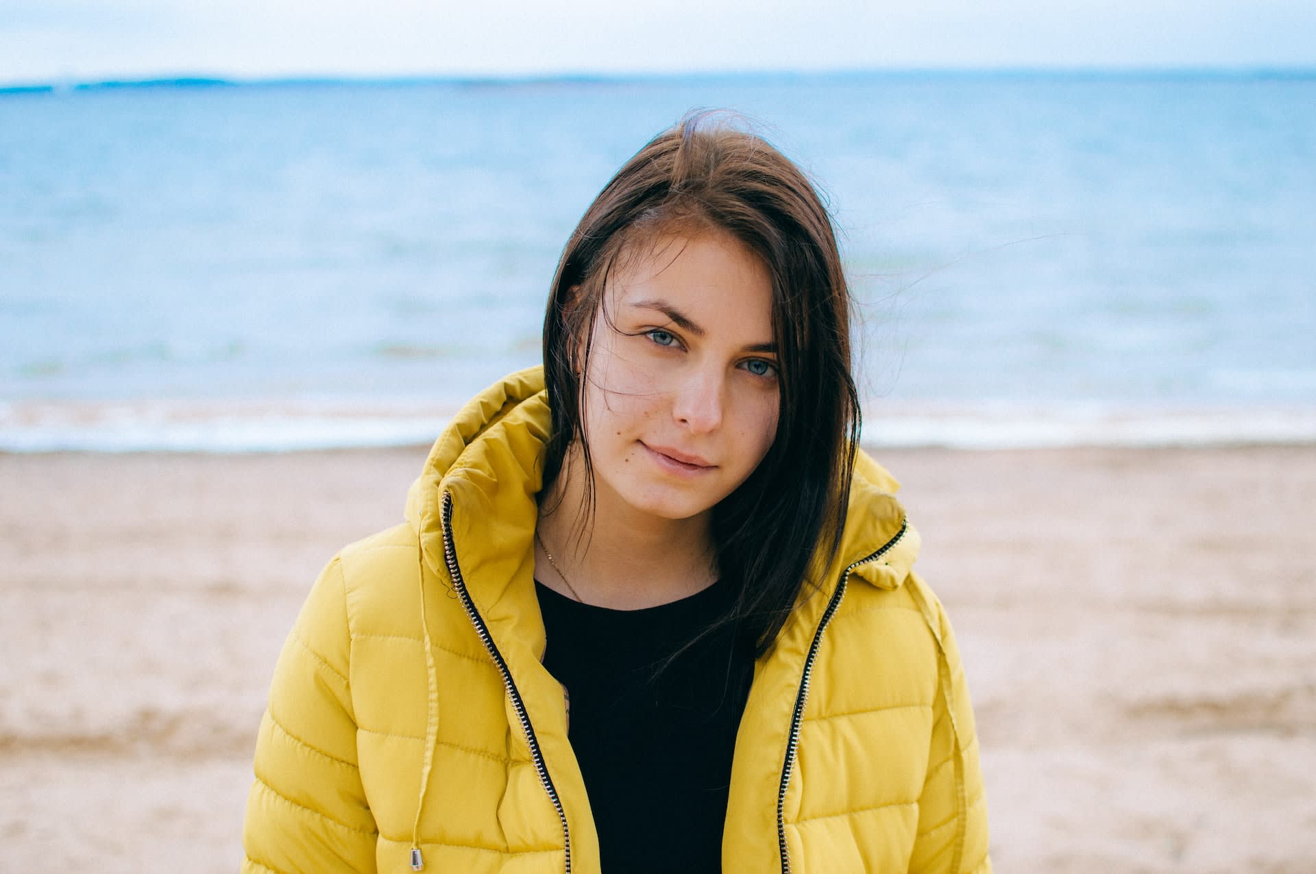 Woman wearing a vintage yellow puffer coat at the beach