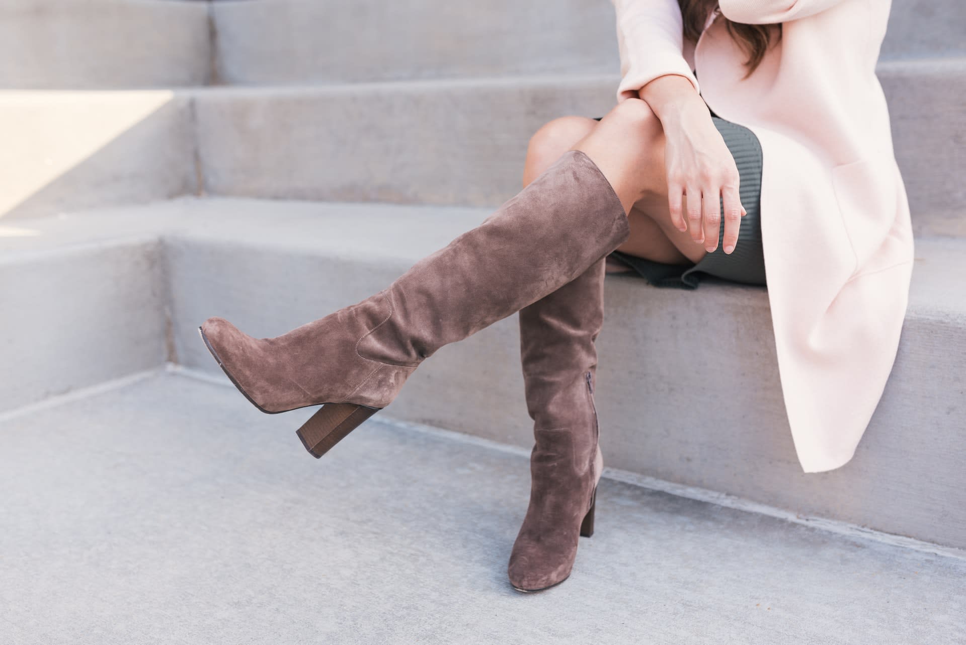 Woman wearing knee-high suede heeled boots