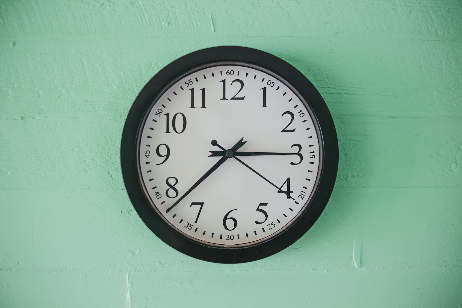 Black clock on a mint green wall