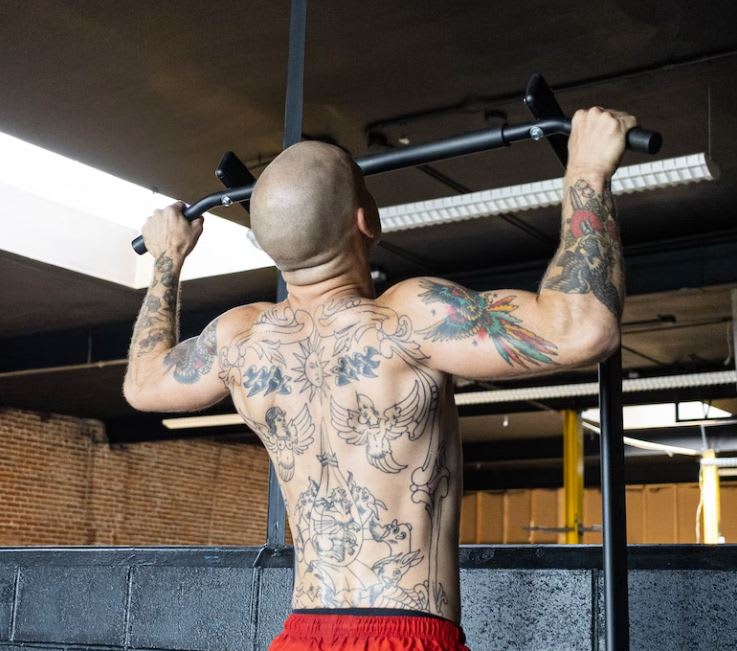 Heavily tattooed man pulling up on a pull up bar