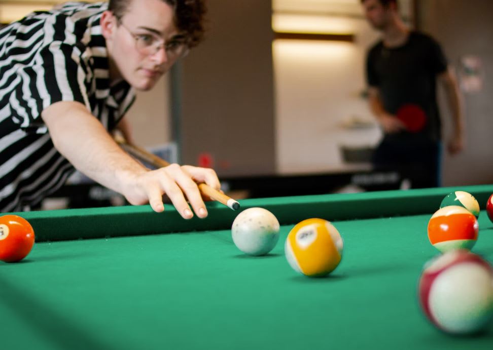 Student playing pool on a pool table