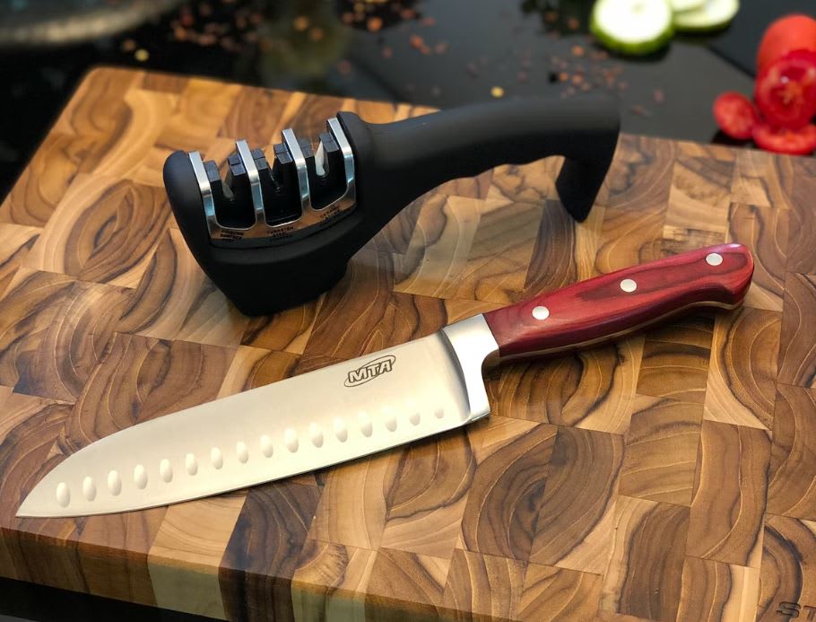 Knife sharpener on a wooden chopping board with a big kitchen knife