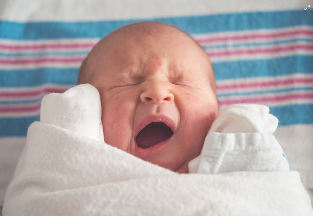 Baby yawning in a swaddle blanket
