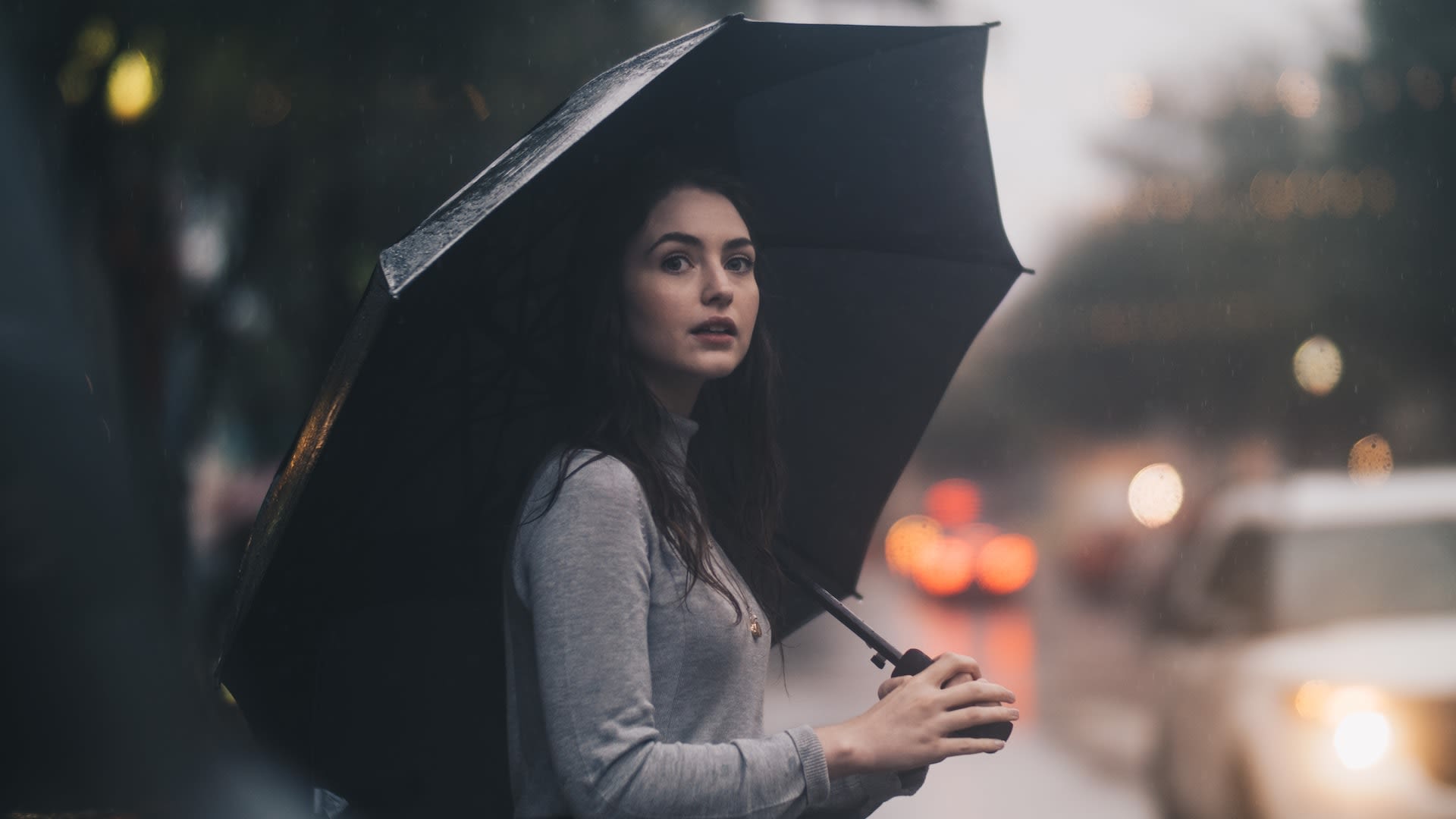 Woman holding a second-hand black umbrella in the rain