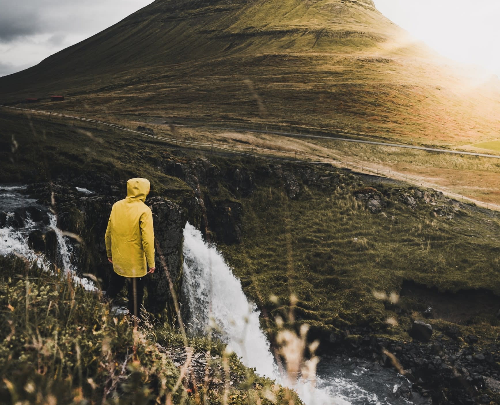 Man wearing a yellow raincoat on a river walk