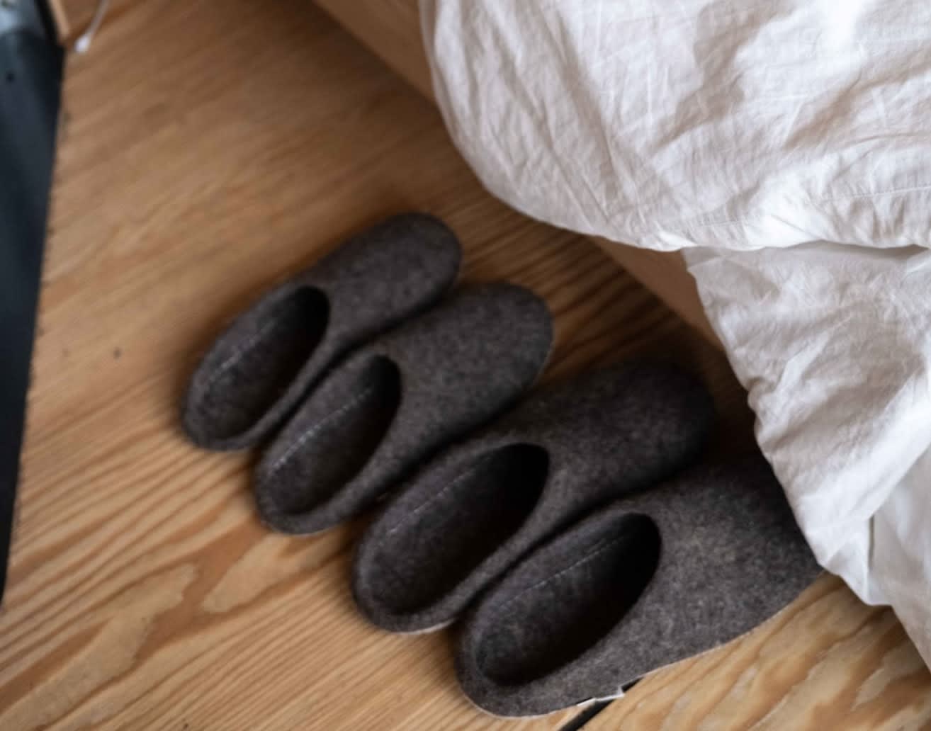 Grey slippers on the floor next to the bed