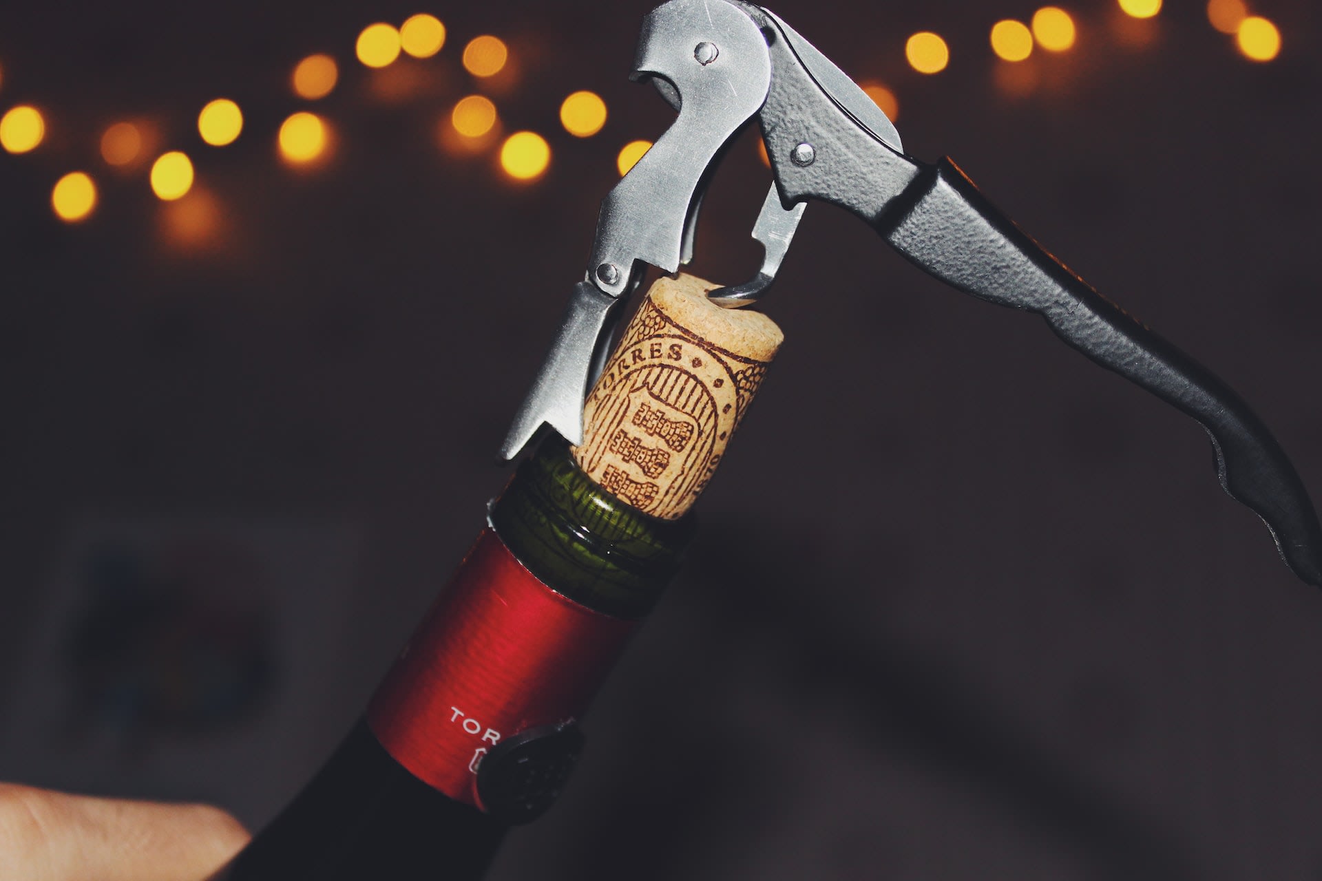 Bottle of red wine being opened with corkscrew