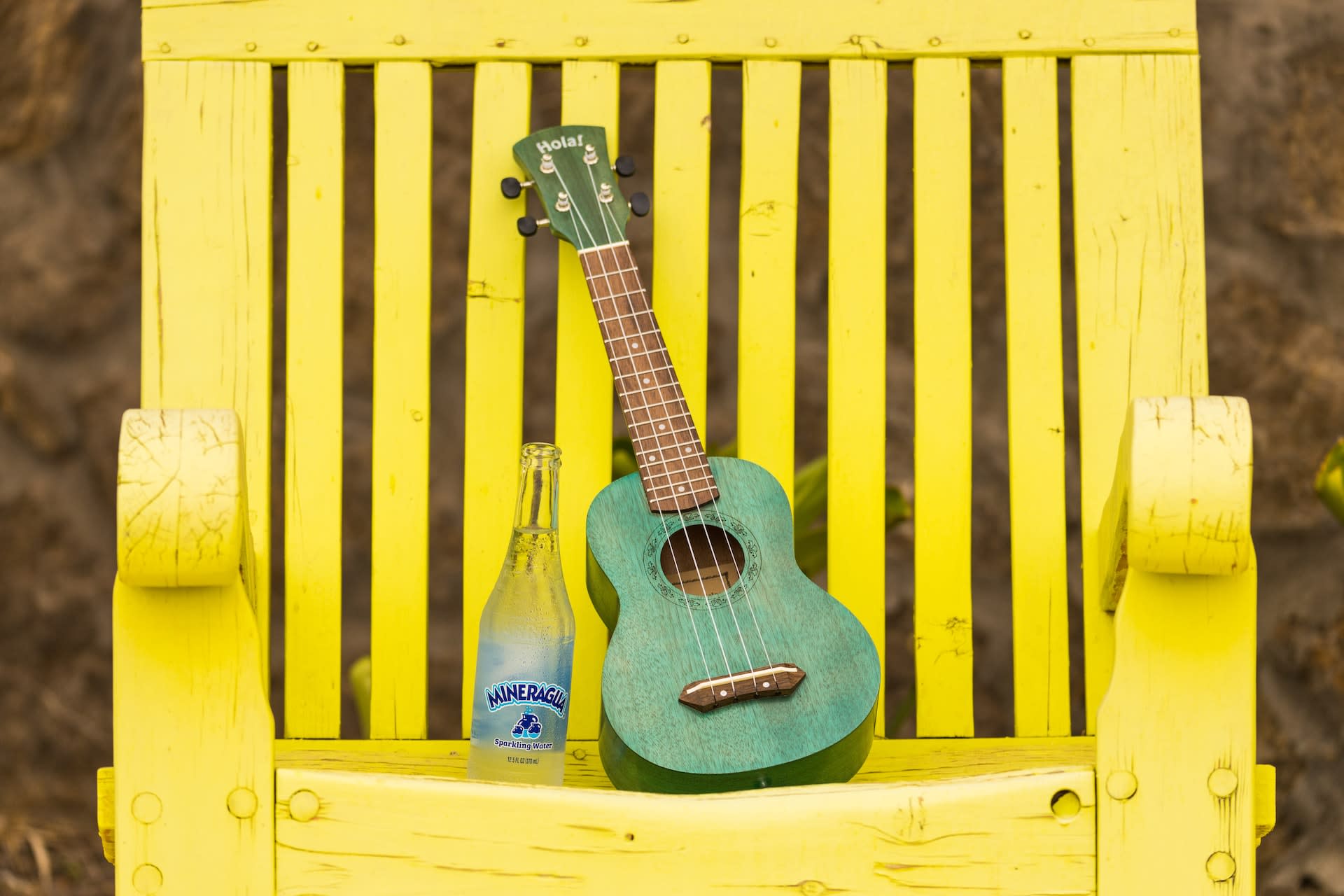 Green second-hand ukelele on a garden chair