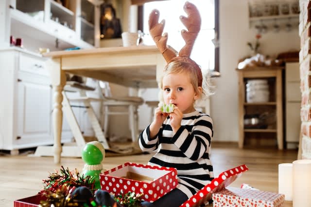 Girl opening Christmas present with reindeer headband on