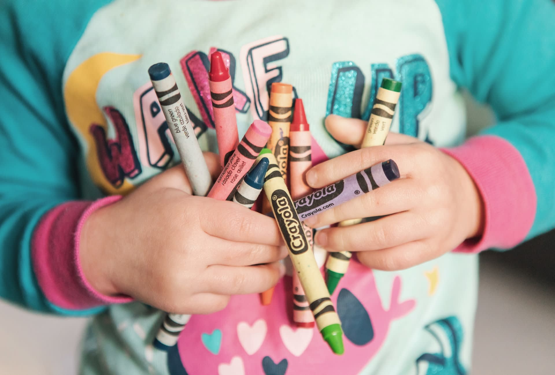 Kid holding lots of crayons