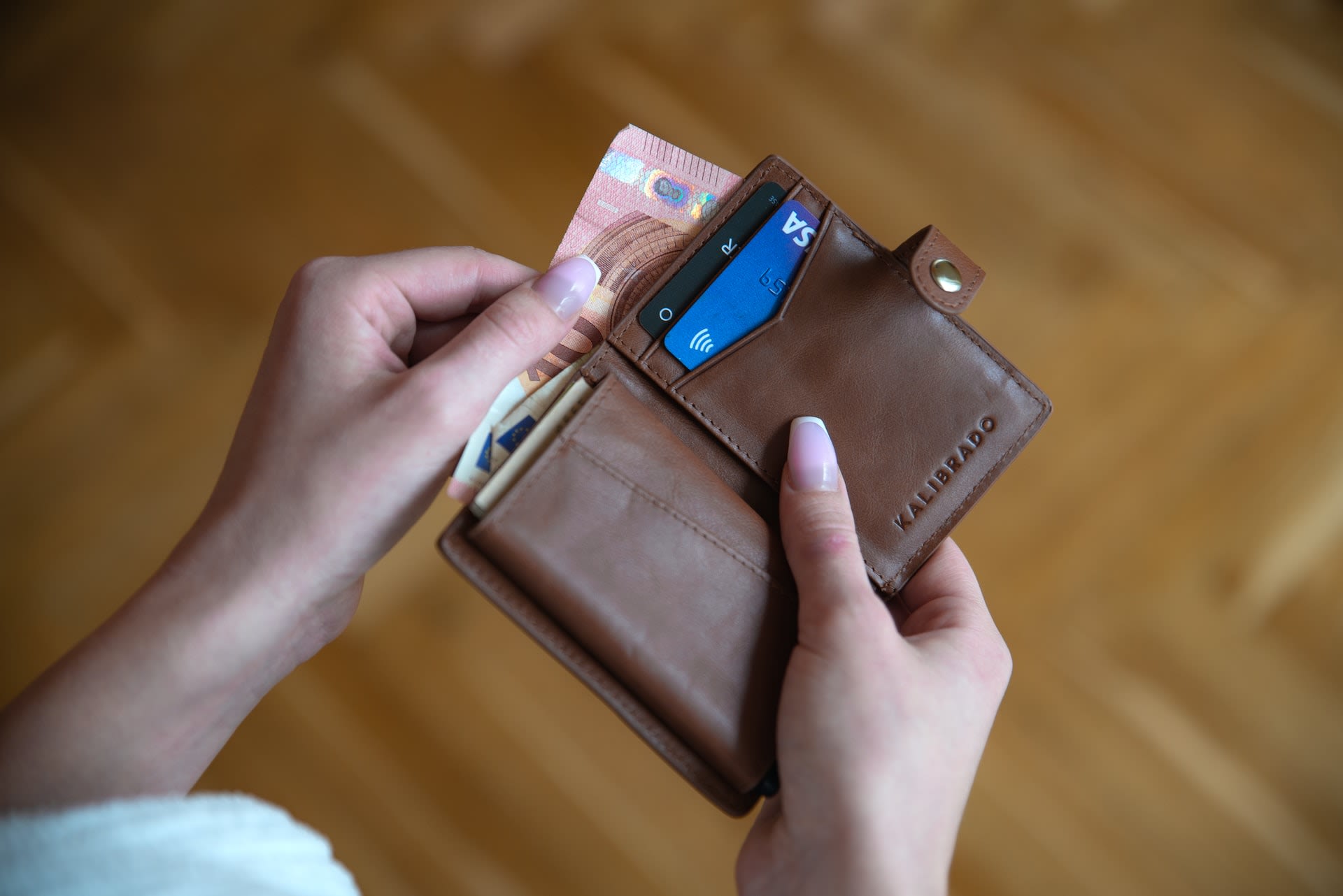 Person holding brown leather wallet