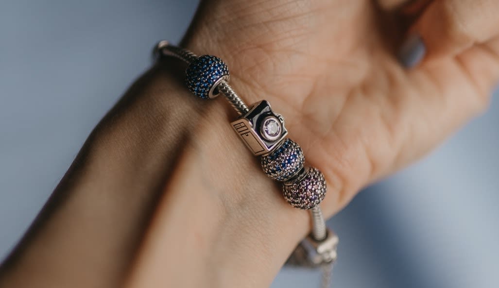 Person wearing silver and black bracelet with charms on