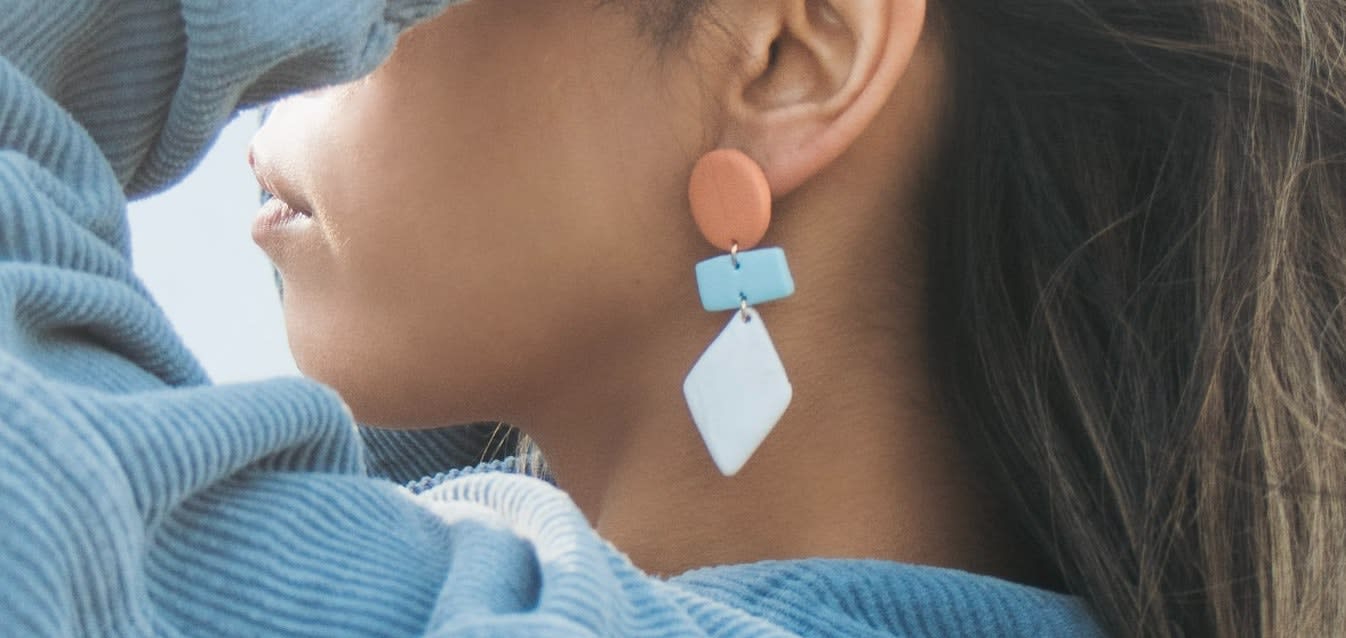 Woman wearing blue and beige earrings