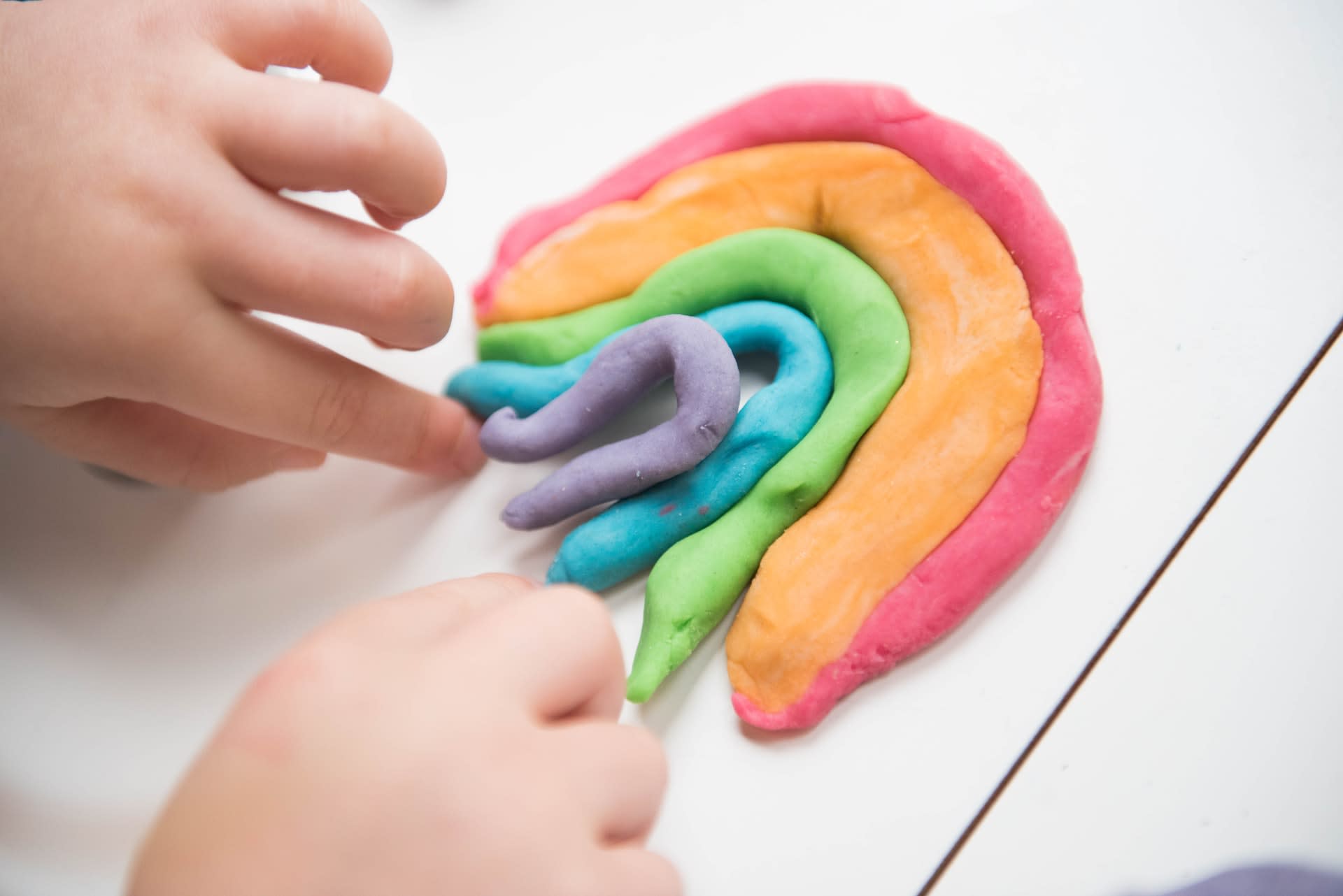 Person creating a rainbow out of play doh