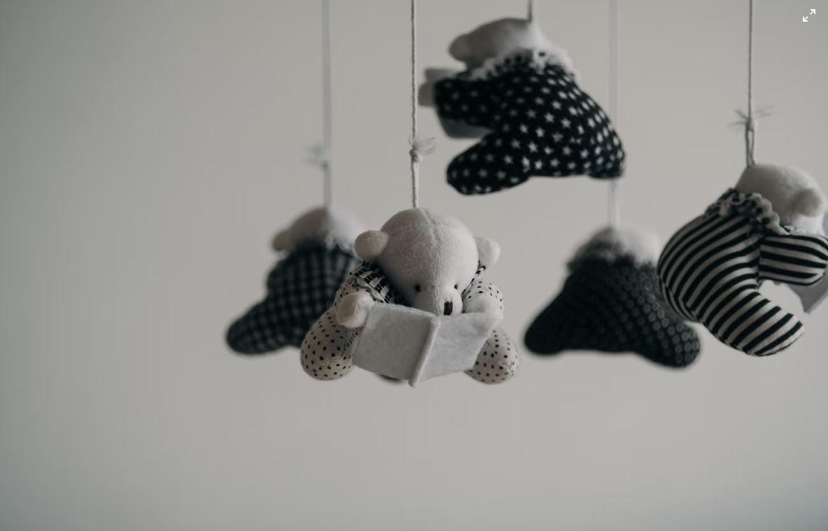 Black and white picture of a preloved baby mobile soft bear reading a book