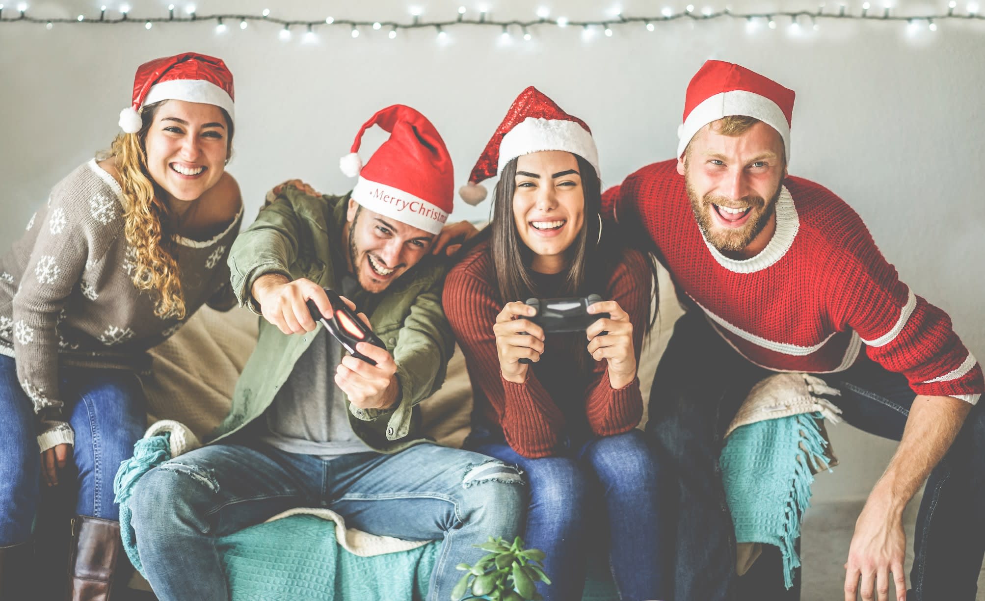 Friends playing console game at Christmas on the sofa