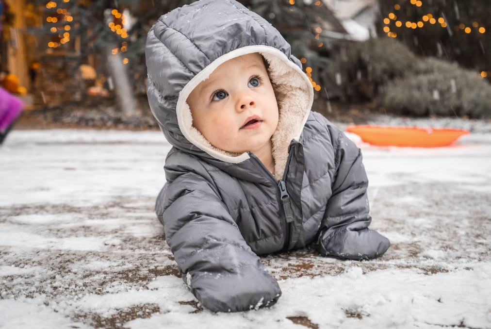 Baby crawling on snowy floor in second hand snow suit