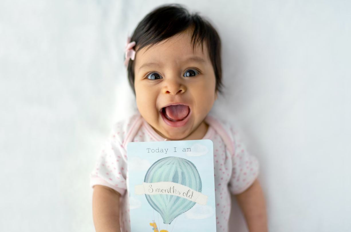 Baby smiling with 3 month milestone card