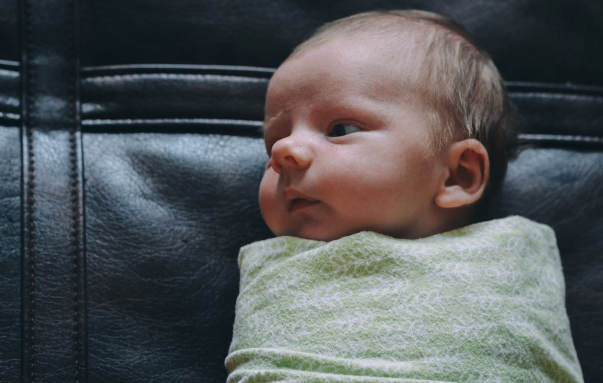 Baby in green swaddle